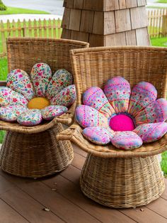 two wicker chairs sitting on top of a wooden deck covered in colorful cushions and pillows