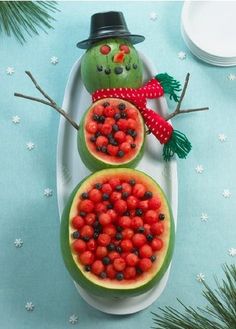 a snowman made out of watermelon is sitting on a plate with berries