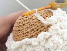 a crocheted object being held in someone's hand with a pair of scissors