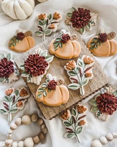 some decorated cookies are laying on a white tablecloth with pumpkins and flowers around them