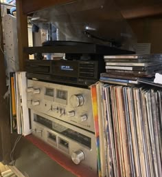 an old stereo player surrounded by records in a room with a metal shelf full of cds