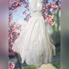 a mannequin wearing a wedding dress in front of a tree with pink flowers