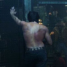 a shirtless man standing in front of a cage