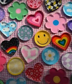 many different colored hearts and smiley faces on a pink checkered tablecloth with flowers