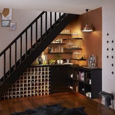 a wine rack under the stairs in a living room next to a stair case filled with bottles and glasses