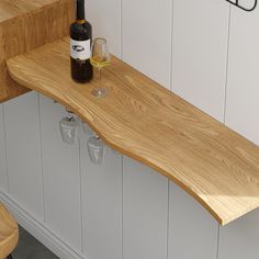 a bottle of wine sitting on top of a wooden counter next to two empty glasses