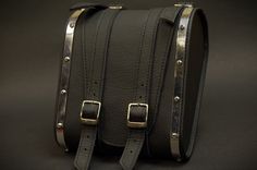 a black leather case with two metal straps