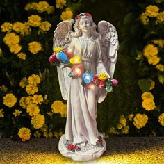 an angel statue with flowers and lights around it