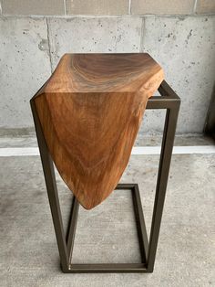 a wooden table sitting on top of a metal stand in front of a cement wall