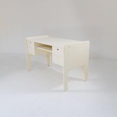 a white desk with two drawers on the bottom and one drawer at the top, against a white wall