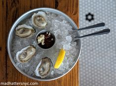 an ice bucket with oysters on it and a lemon wedge in the bowl next to it