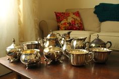 a table topped with lots of silver pots and pans on top of a wooden table