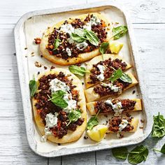 an overhead view of some food on a baking sheet with spinach leaves and cheese