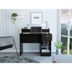 a black desk with a laptop on it in front of a window and potted plant