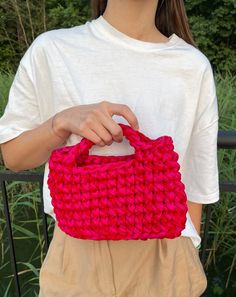 a woman is holding a red purse in her hands