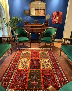 a living room filled with green couches and chairs next to a rug on top of a hard wood floor