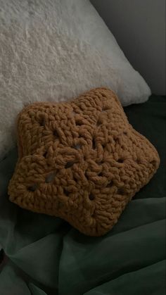 a brown crocheted pillow sitting on top of a bed