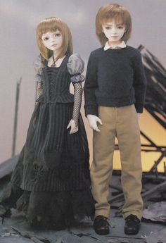 two dolls standing next to each other on top of a pile of rubble and debris