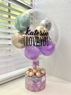 a cake topped with lots of balloons next to a window