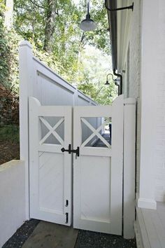 an open white door leading to a house with a light on the side and trees in the background