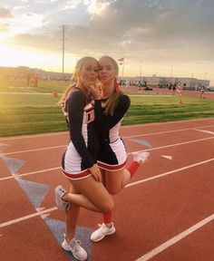 two cheerleaders pose for a photo on the track