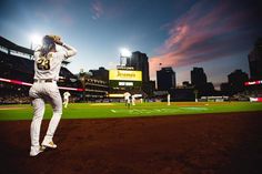 a baseball player standing on top of a field next to a stadium filled with people