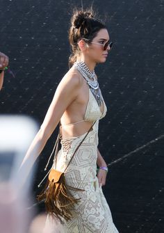 a woman in a white dress walking down the street with her hand on her hip