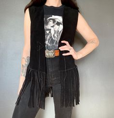 1970s suede fringed vest *Black color.  *Thick suede *Fringed *open front with tie *Good but used vintage condition. Shows normal signs of age and wear. ERA: 1970s LABEL: None SIZE: Would fit a size S-M-L (please check measurements) Shown on a size S FABRIC: Suede Measurements are taken flat and must be doubled: Waistcoat: Chest: 48 cm x 2 Length (fringe included): 78 cm Length (fringe not included): 52 cm Shoulder to shoulder: 38 cm   If you have any questions regarding this item please contact Suede Fringe Vest, Fringe Vest, Suede Fringe, Vest Outfits, Western Outfits, Womens Vest, Black Suede, Black Color, 1970s