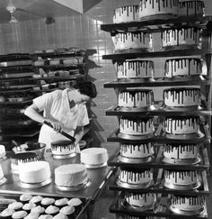 black and white photograph of a woman decorating cakes in a kitchen with chocolate drips