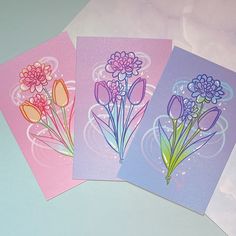 three cards with flowers on them sitting next to each other