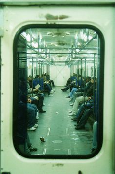 the inside of a subway car with lots of people sitting on it's seats