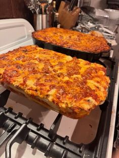 two pans of pizza sitting on top of an oven