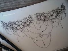 a drawing of flowers and chains on a piece of paper with a pen next to it