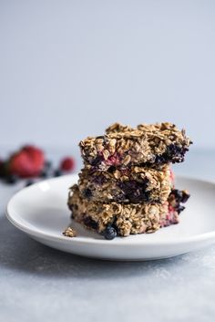 two granola bars stacked on top of each other with blueberries and raspberries in the background