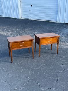 two small wooden tables sitting next to each other on cement floored area with garage door in background