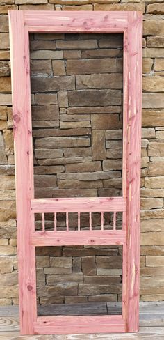 a wooden bed frame sitting in front of a stone wall