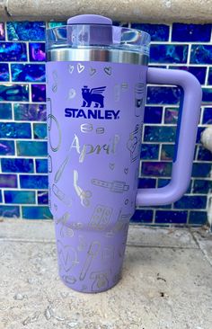 a purple tumbler cup sitting on top of a tile floor next to a blue tiled wall