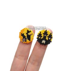 two fingers with beaded designs on them, one has a black cat and the other is