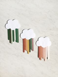 three wooden sticks with clouds on them sitting next to each other in front of a marble surface