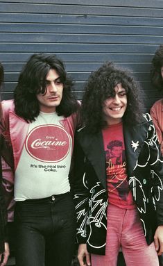 three young men standing next to each other in front of a garage door wearing jackets