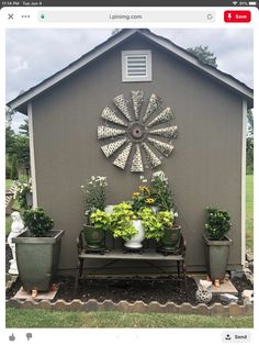 a garden shed with potted plants and a bench in the front yard on a cloudy day