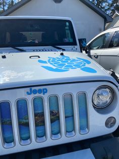 a jeep parked in front of a house with a turtle decal on the hood