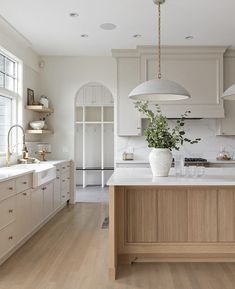 a large kitchen with white cabinets and wooden flooring, along with an island in the middle