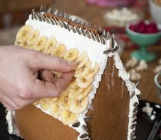 a person is decorating a cake with bananas on the icing and frosting