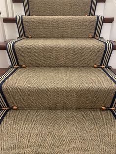 a carpeted stair with blue trim and brown handrails on the bottom step