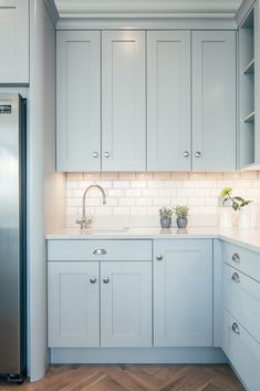 a kitchen with light blue cabinets and white counter tops, along with wooden flooring