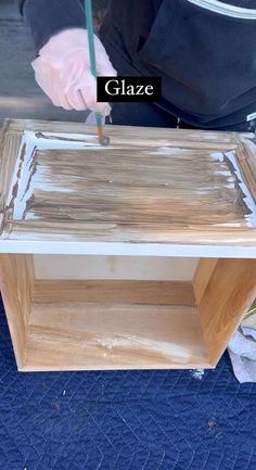 a person in white gloves is painting a wooden cabinet with paint and wood shaving