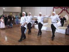 two men in white turbans dancing on a dance floor with other people watching