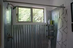 a bathroom with a shower, window and towel rack in front of the tub door