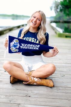 a woman sitting on the ground holding up a blue scarf that says, florida southern